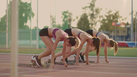 Three-female-athletes-simultaneously-start-running-marathon-rivalry-slow-motion.-women-standing-on-a-starting-line-before-race